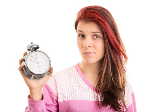 Young woman holding alarm clock