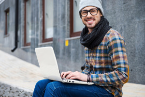 Millennial man on street with computer