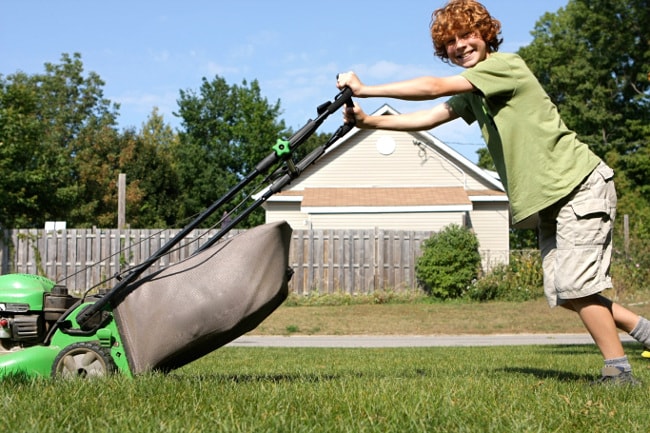 Teenaged boy mowing lawn