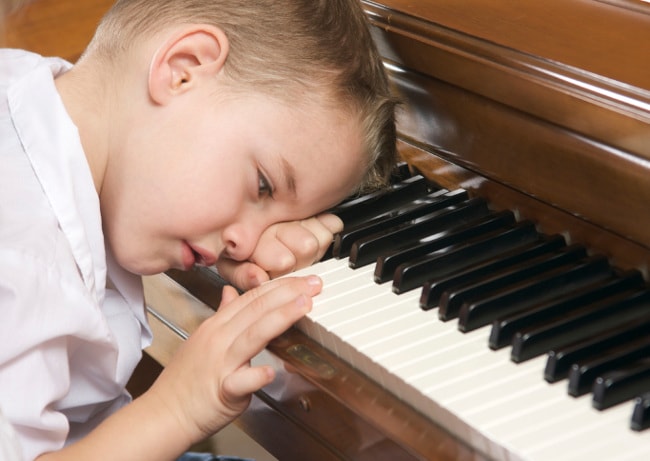 Young boy procrastinating at piano